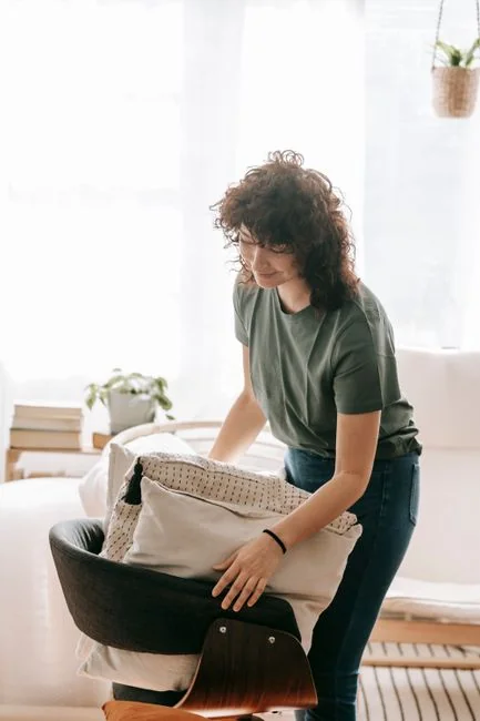 why-choose-us A hotel housekeeper neatly stacks fresh towels in a luxurious room setting.